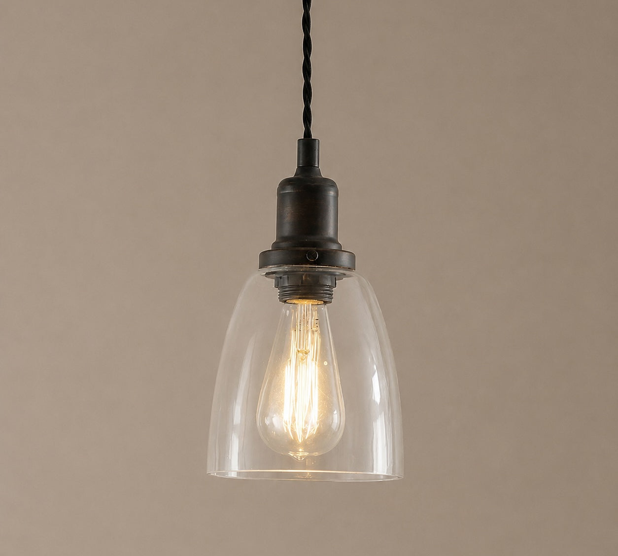 Vintage-style pendant light with clear glass shade and black metal fixture on a beige background