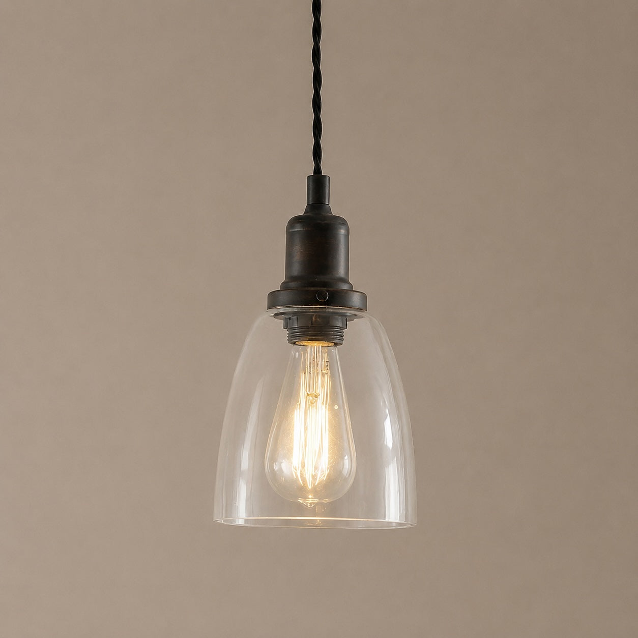 Vintage-style pendant light with clear glass shade and black metal fixture on a beige background