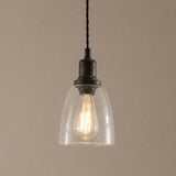 Vintage-style pendant light with clear glass shade and black metal fixture on a beige background