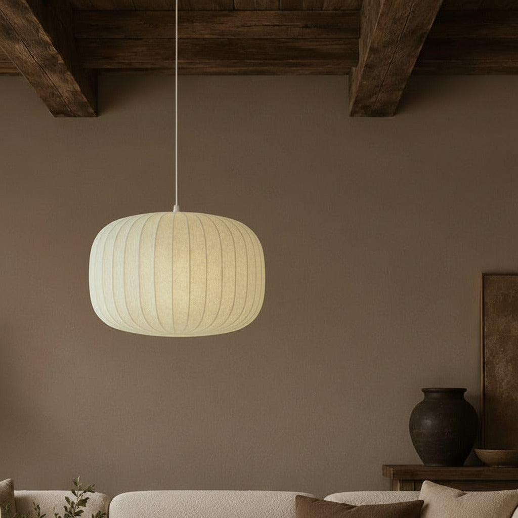 Pendant light hanging above a sofa in a room with a vase and plant on a table.