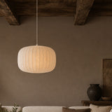 Pendant light hanging above a sofa in a room with a vase and plant on a table.