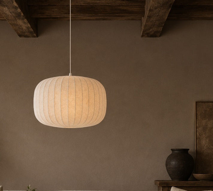 Pendant light hanging above a sofa in a room with a vase and plant on a table.