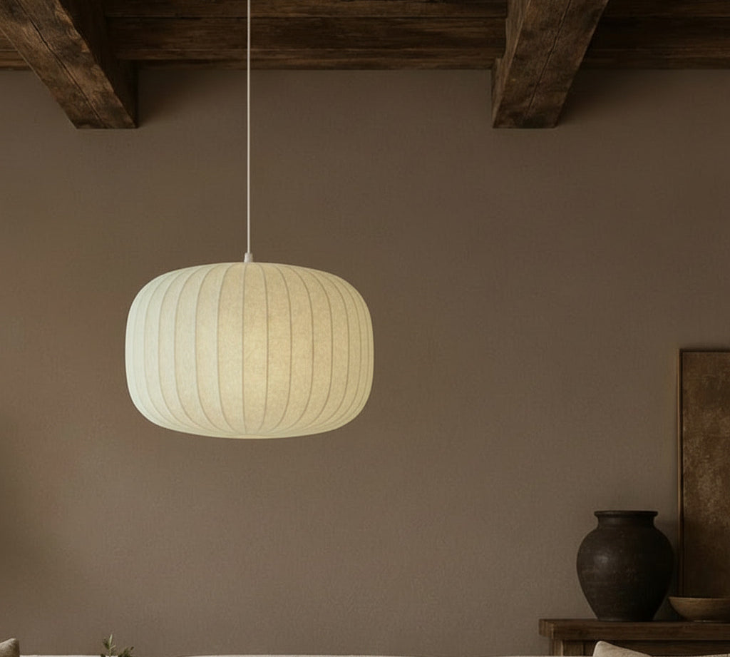 Pendant light hanging above a sofa in a room with a vase and plant on a table.