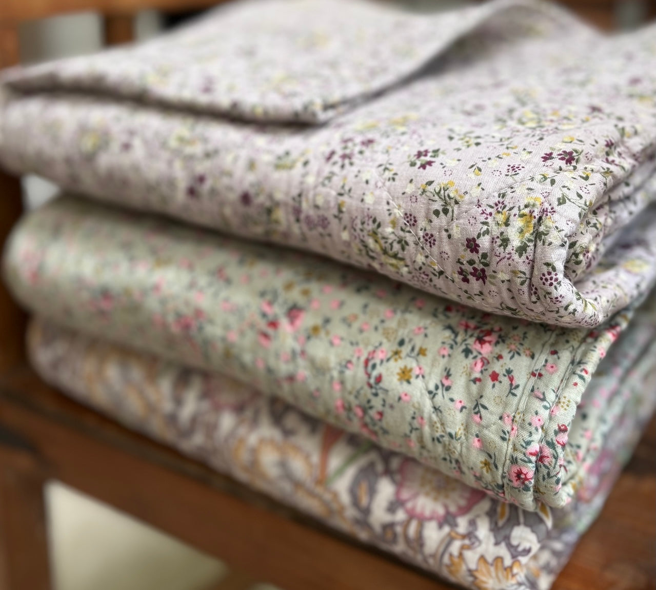 Stack of floral-patterned quilts on a wooden surface