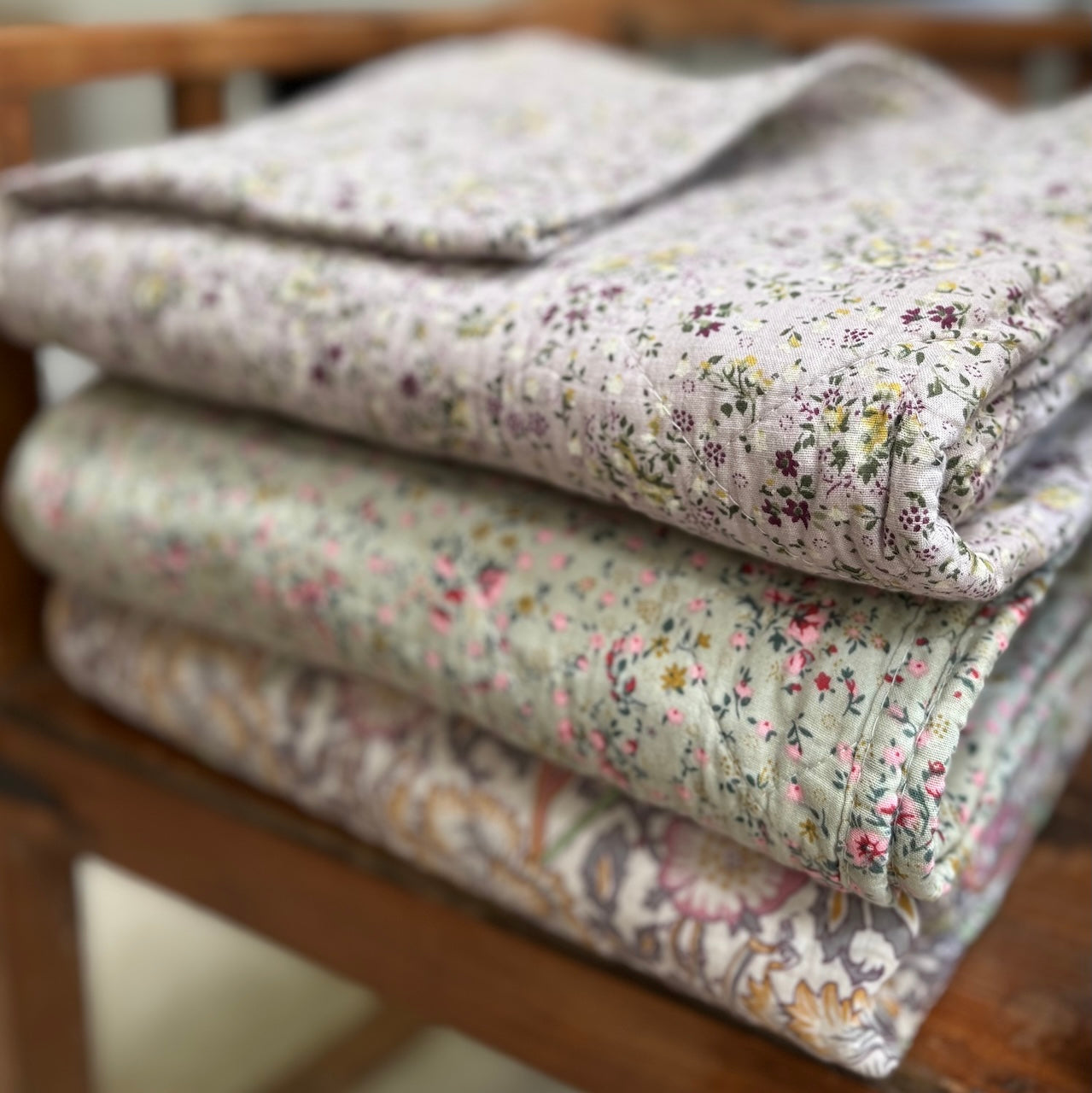 Stack of floral-patterned quilts on a wooden surface