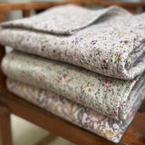 Stack of floral-patterned quilts on a wooden surface