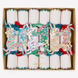 A boxed set of Christmas crackers ornaments arranged in a square cardboard tray. Each cracker is decorated with a different colorful floral and whimsical pattern, tied with a ribbon, and some have gold foil text.