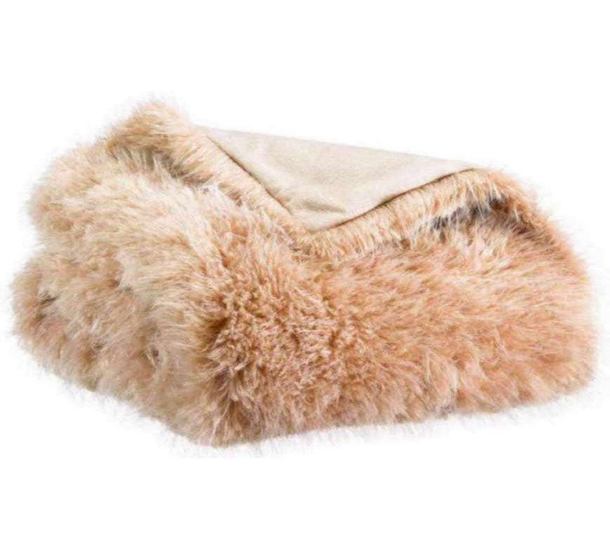 A folded faux fur throw blanket in a light tan color, showing its soft, shaggy texture and a solid beige reverse side, set against a plain white background.