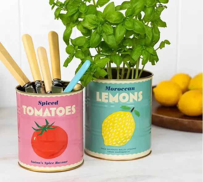 Two repurposed canisters with planters and kitchen utensils on a white surface.