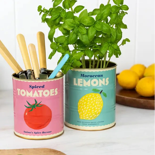 Two repurposed canisters with planters and kitchen utensils on a white surface.