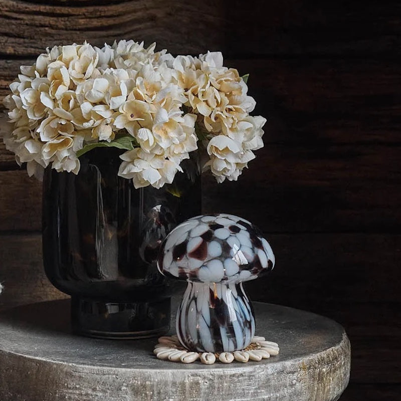 Decorative mushroom lamp on a wooden surface with flowers in the background