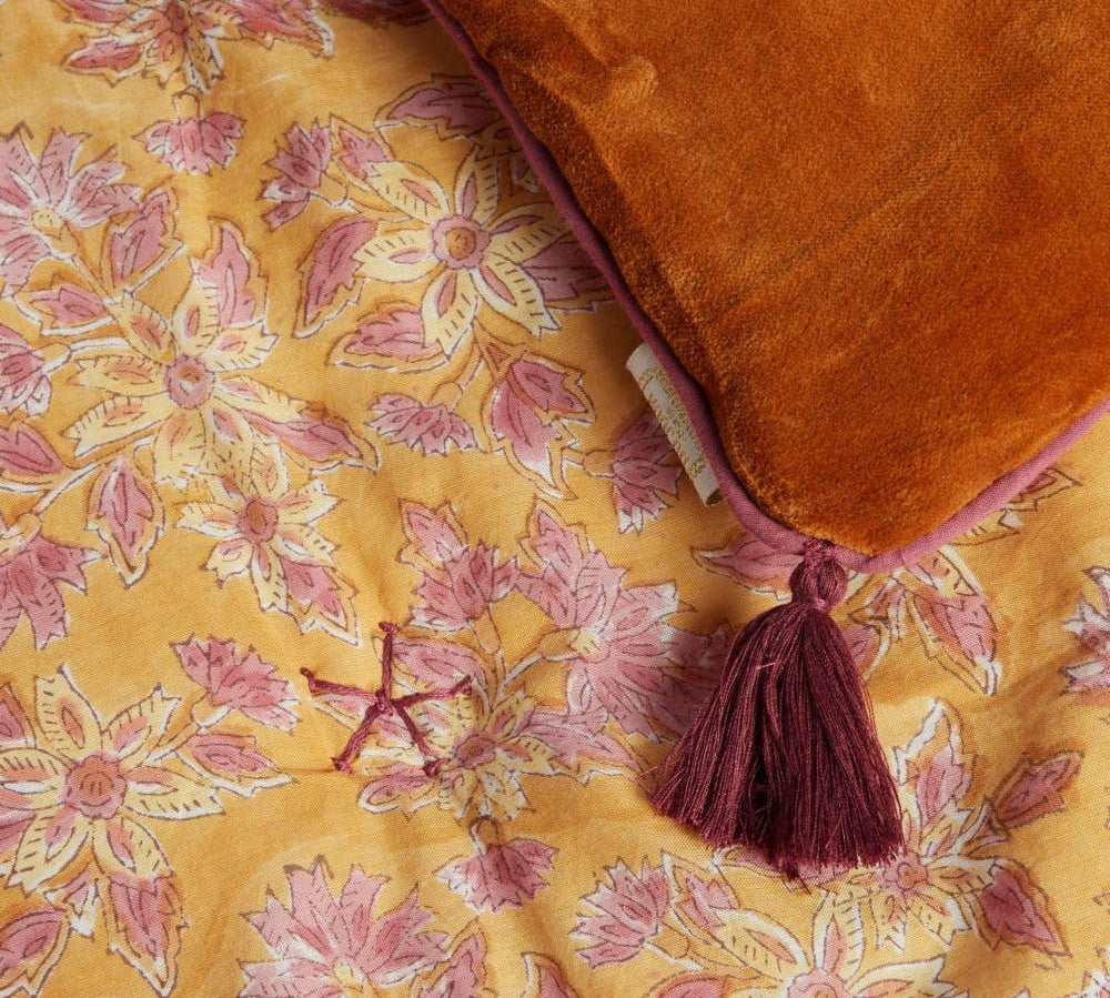 Orange throw with tassel on a yellow floral fabric