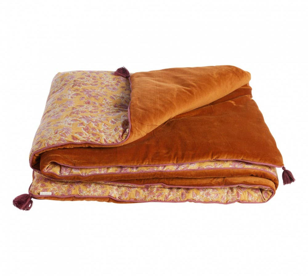 Folded orange blanket with floral pattern on a white background