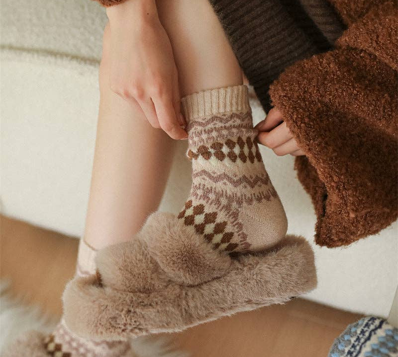 Person wearing patterned socks with fluffy cuffs, sitting on a wooden floor.