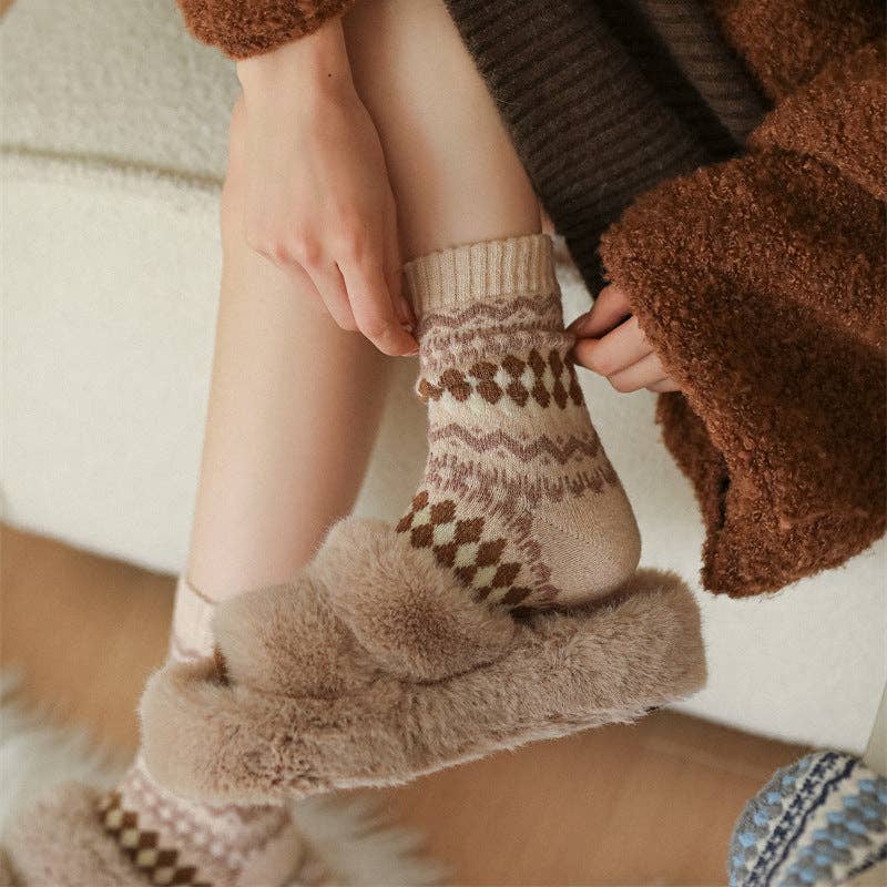 Person wearing patterned socks with fluffy cuffs, sitting on a wooden floor.