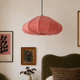 Pink pendant lamp hanging above a bed with decorative elements on a wall.
