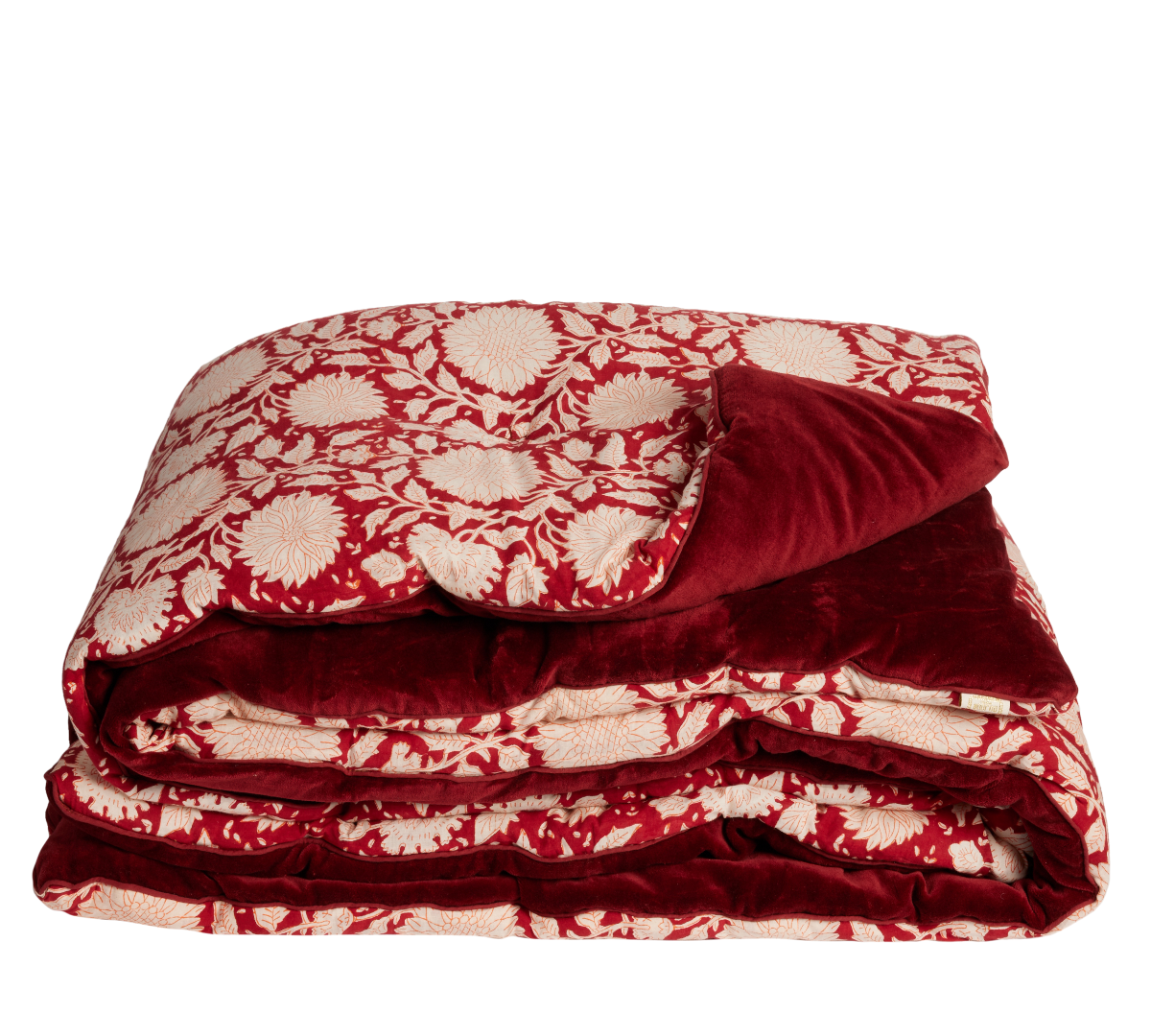 A folded plush throw eaturing a red and cream floral pattern on one side and a solid deep red velvet reverse side, shown against a plain white background.