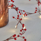 Battery operated white leaf and copper wire string lights with red jewel clusters, designed for Christmas or dinner parties.