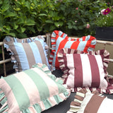 Colorful striped pillows with ruffled edges on a chair outdoors.