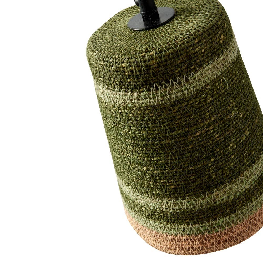 A close-up of a woven cylindrical product, likely a lampshade or decorative cover, in olive green and light beige horizontal stripes with a black top cap, shown on a white background.