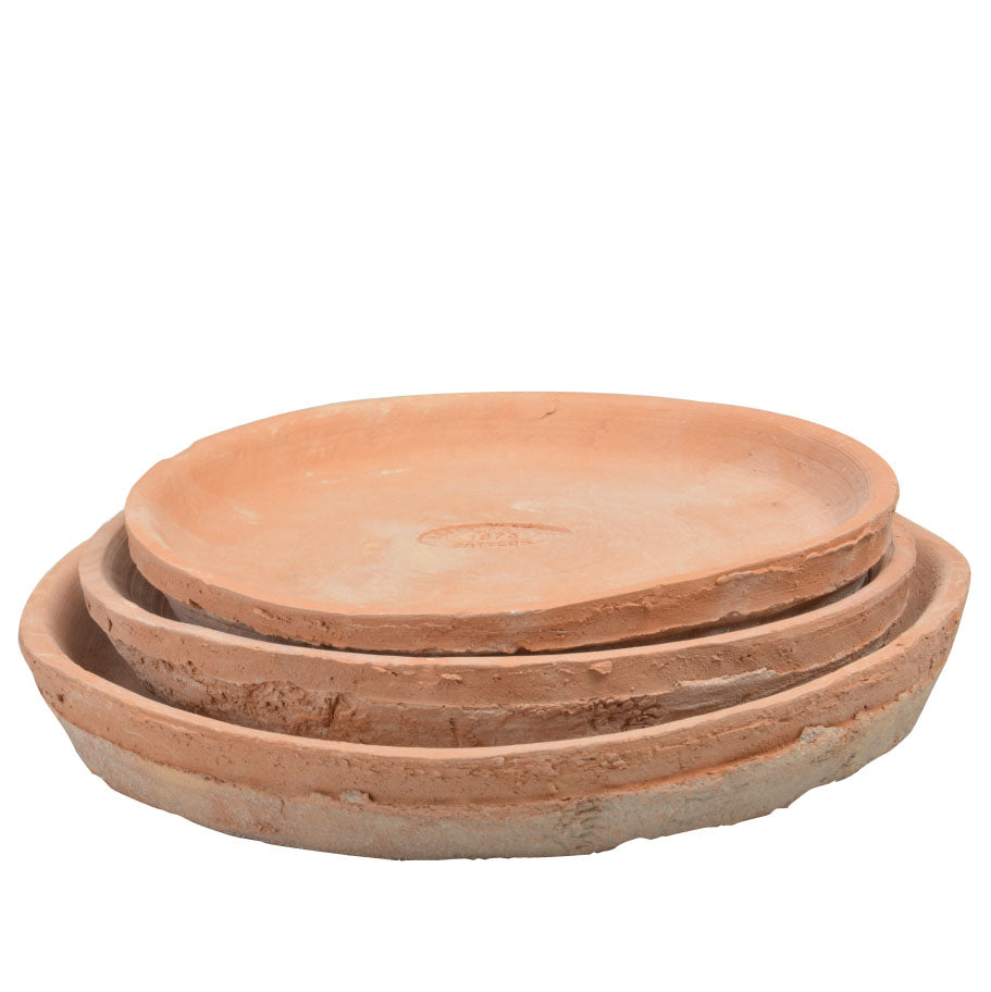 Set of three terracotta saucers stacked on a white background