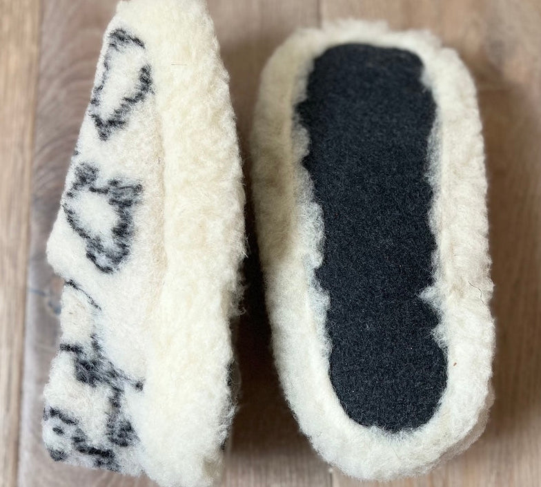 Pair of white slippers with black sole on a wooden floor