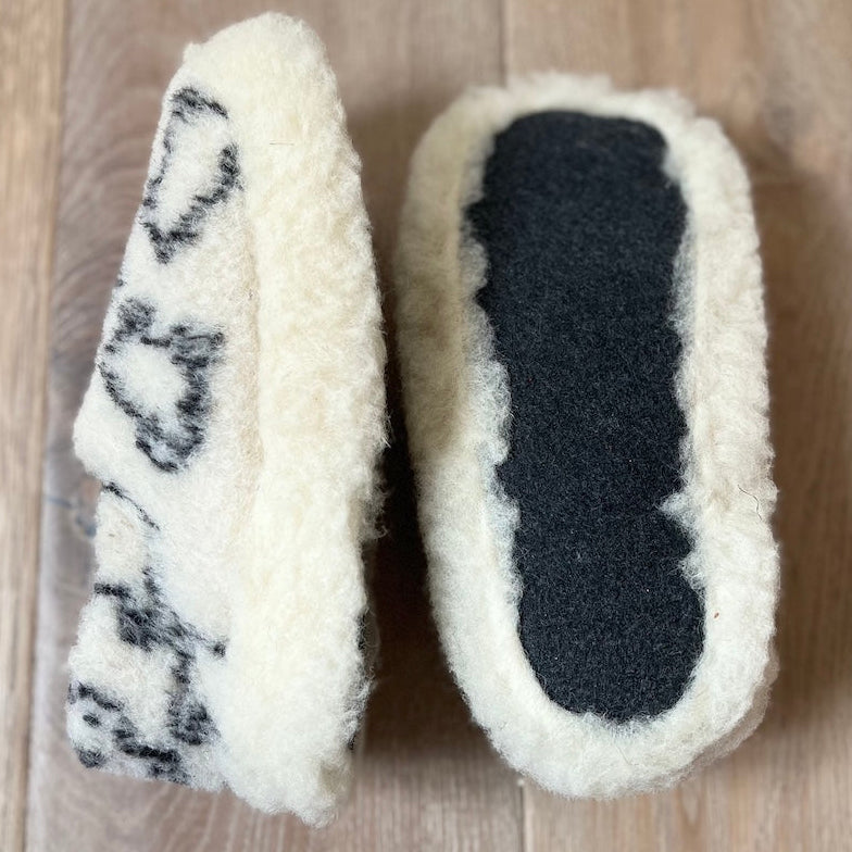 Pair of white slippers with black sole on a wooden floor