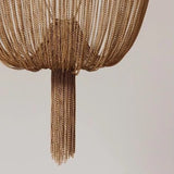 Close-up of a gold chain chandelier against a neutral background