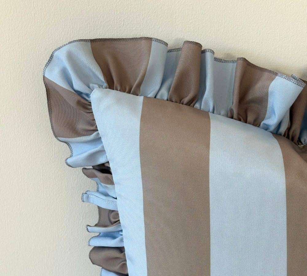 Striped cushion with brown, white, and gray pattern on a beige background
