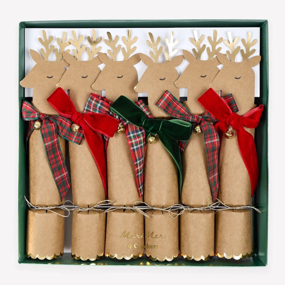 A set of six Christmas cracker ornaments in a dark green gift box. Each cracker is shaped like a reindeer with a brown kraft paper body, gold glitter antlers, and a ribbon bow in red, green, or plaid.