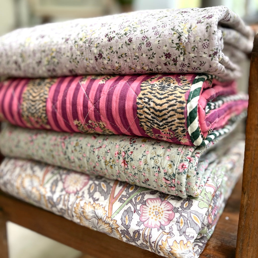 Stack of patterned quilts on a wooden surface