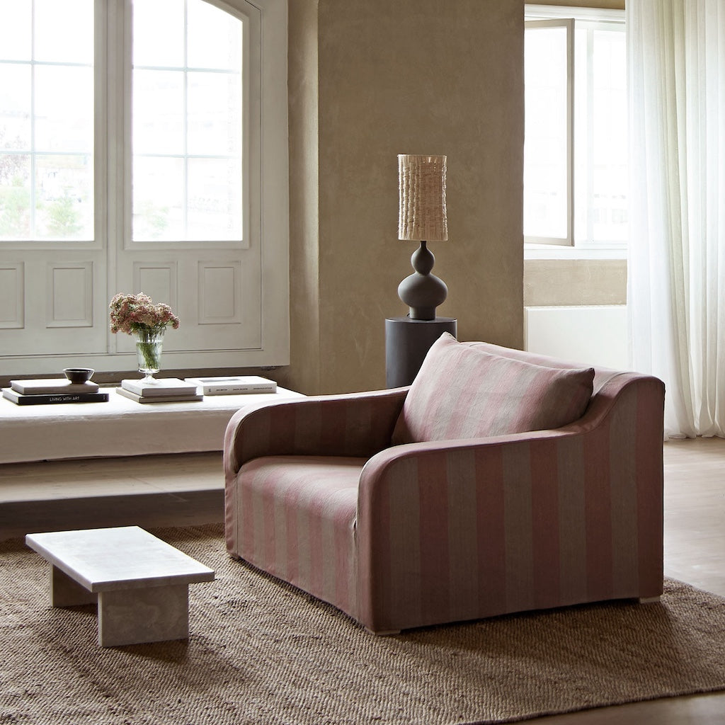 Pink striped sofa in a living room with a lamp and decor items.