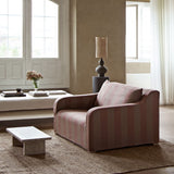 Pink striped sofa in a living room with a lamp and decor items.