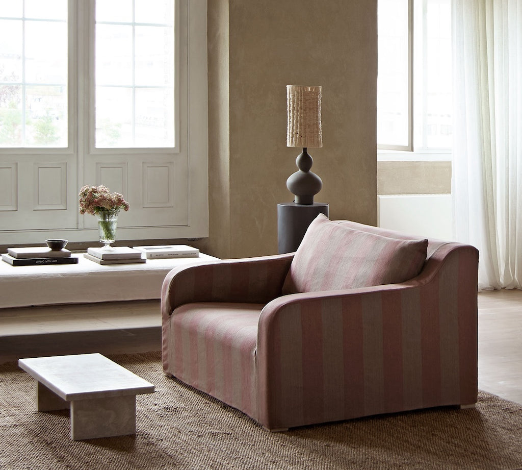 Pink striped sofa in a living room with a lamp and decor items.