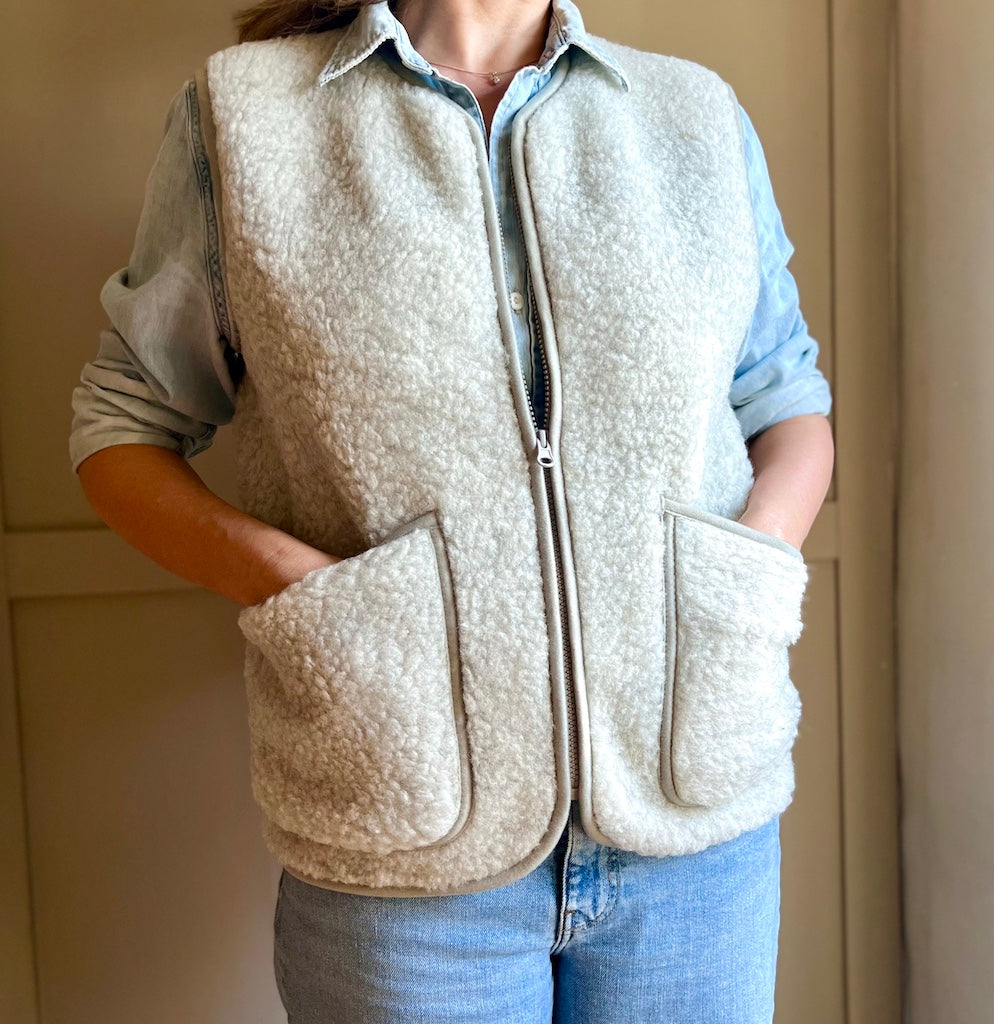 Person wearing a grey fleece vest with a neutral background