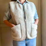 Person wearing a grey fleece vest with a neutral background