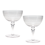 Two clear cut-glass coupe glasses with etched geometric patterns on the bowls and stems, shown on a plain white background.
