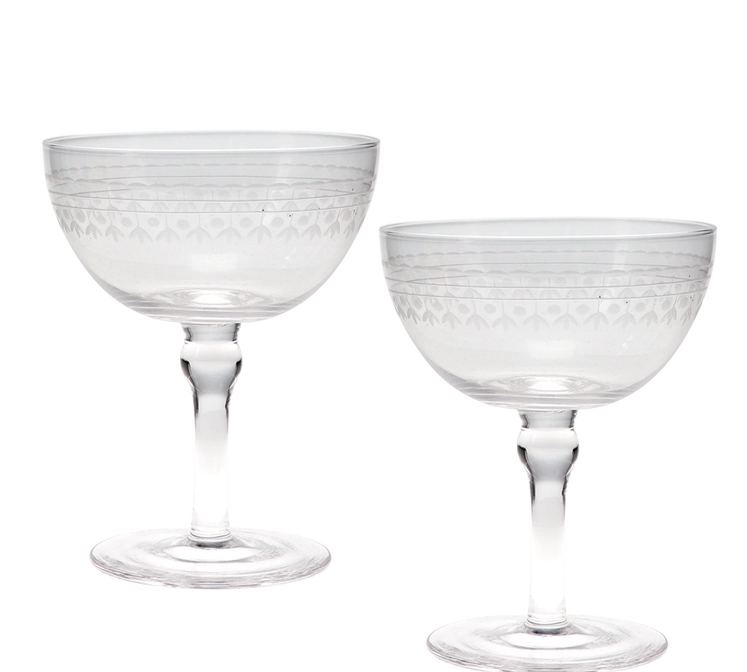 Two clear cut-glass coupe glasses with etched geometric patterns on the bowls and stems, shown on a plain white background.