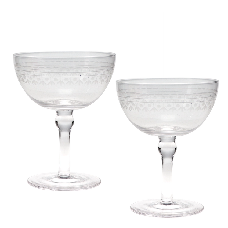 Two clear cut-glass coupe glasses with etched geometric patterns on the bowls and stems, shown on a plain white background.