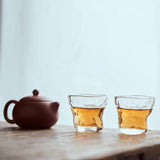Tea set with a teapot and two glass cups on a wooden surface.