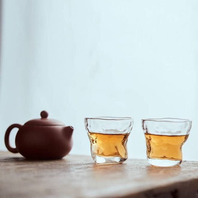 Tea set with a teapot and two glass cups on a wooden surface.