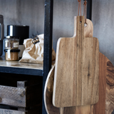 Wooden cutting boards hanging on a wall with a rustic background