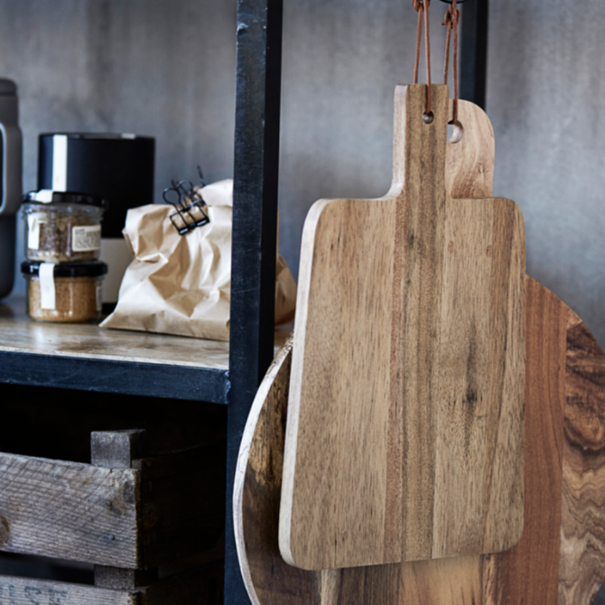 Wooden cutting boards hanging on a wall with a rustic background